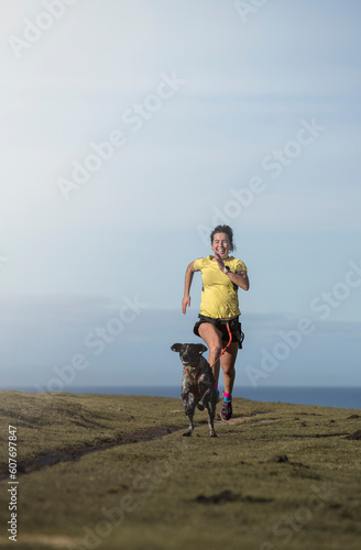 Woman practicing canicross with dog on grass photo