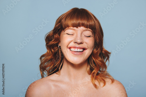 Happy woman with ginger hair and flawless skin smiling with her eyes closed photo