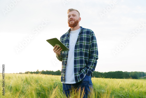An agronomist with a tablet is standing in the field. Checking the quality of the future harvest. Preparing for the food crisis