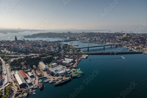 Aerial view of a boat sailing the Golden Horn waterway with Ataturk Bridge and Galata Bridge connecting the European Side of Istanbul downtown, Turkey. photo