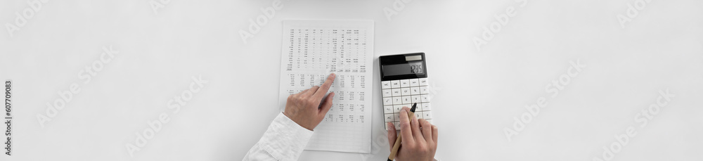Woman using a calculator and points her finger at the numbers in the financial documents. Financial,business and money concept. Top view. Woman using a calculator and points her finger at the numbers in the financial documents. Financial,business and money concept. Top view.