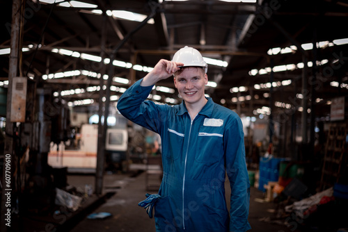 Portrait engineer worker industry wearing safety uniform pose standing at factory workplace with industry hi -machine background. © APchanel
