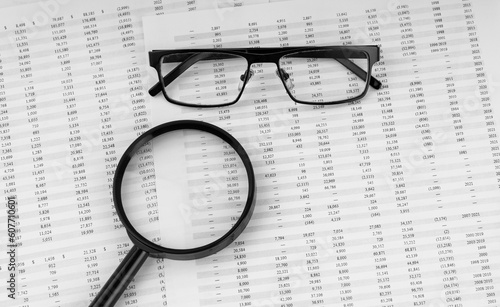 Magnifying glass and eye glasses on financial documents.