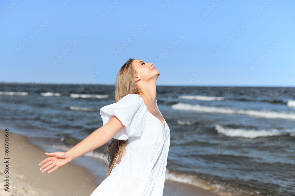 Happy smiling beautiful woman is on the ocean beach in a white summer dress, open arms. Happy smiling beautiful woman is on the ocean beach in a white summer dress, open arms.