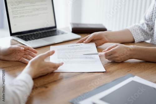 Businesswoman lawyer pointing into contract special points admitting something for colleague or client at the wooden desk in office. Business people teamwork and partnership, meeting concept.