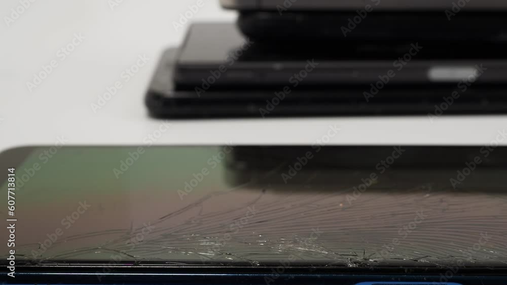 Damaged mobile phones. A bunch of broken smartphones. Used phones on a light background. Damaged mobile phones. A bunch of broken smartphones. Used phones on a light background.