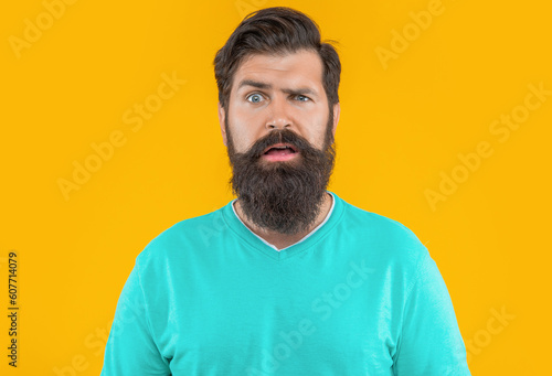 portrait of puzzled bearded man isolated on yellow studio background