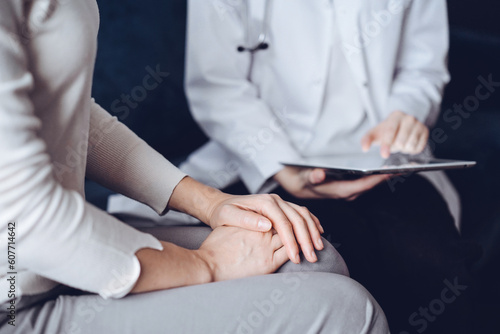 Doctor and patient sitting at sofa in clinic office. The focus is on female woman s hands  close up. Medicine concept.