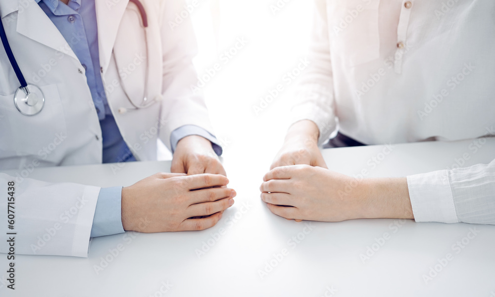 Doctor and patient discussing current health questions while sitting near of each other at the table in clinic, just hands closeup. Medicine concept. Doctor and patient discussing current health questions while sitting near of each other at the table in clinic, just hands closeup. Medicine concept.