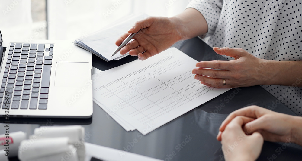 Woman accountant using a calculator and laptop computer while counting taxes for a client. Business audit and finance concepts. Woman accountant using a calculator and laptop computer while counting taxes for a client. Business audit and finance concepts.