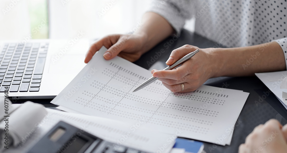 Female accountant pointing with a pen into audit paper while explaining tax counting results, close up. Business audit and finance concepts. Female accountant pointing with a pen into audit paper while explaining tax counting results, close up. Business audit and finance concepts.