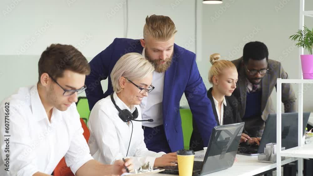 friendly team of colleagues works in the office, people in formal clothes sit at the table and use laptops for work.