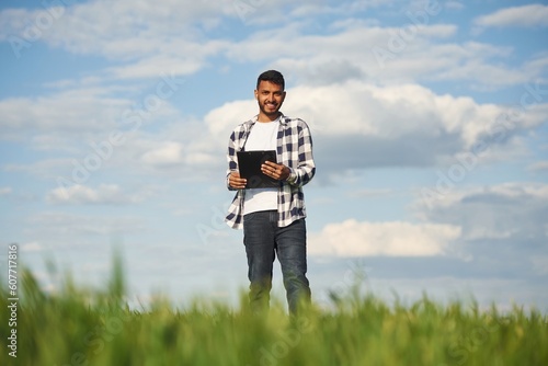 Cloudy sky on background. Handsome Indian man is on the agricultural field