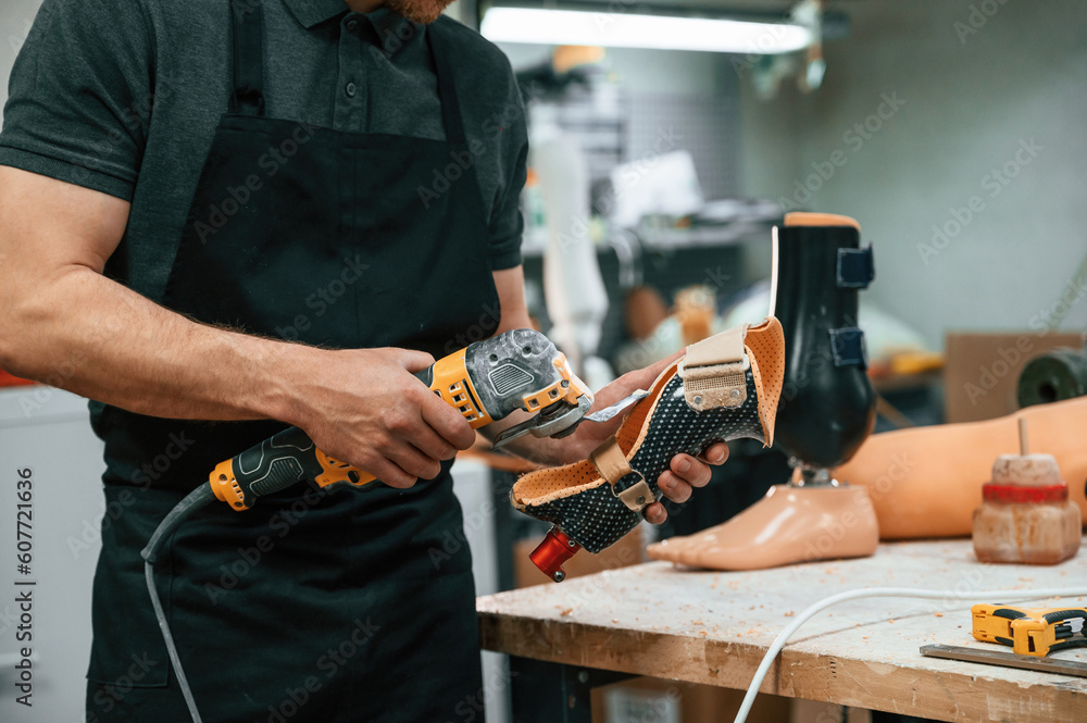 Cuts the material with drill. Technician working with prosthesis in modern laboratory Cuts the material with drill. Technician working with prosthesis in modern laboratory