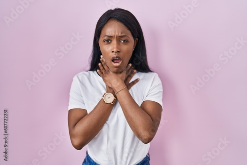 African young woman wearing casual white t shirt shouting suffocate because painful strangle. health problem. asphyxiate and suicide concept.