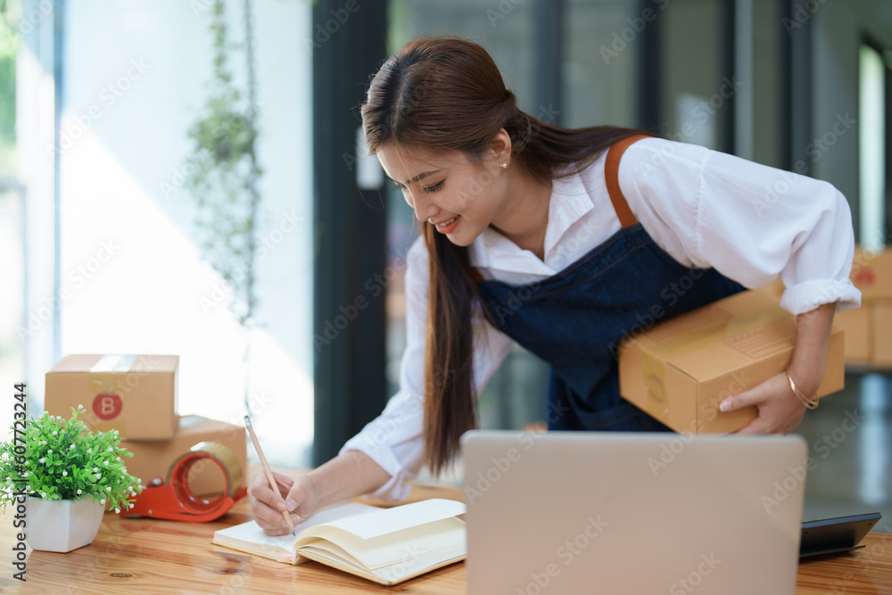 Starting small business entrepreneur of independent young Asian woman online seller is using computer and taking orders to pack products for delivery to customers. SME delivery concept Starting small business entrepreneur of independent young Asian woman online seller is using computer and taking orders to pack products for delivery to customers. SME delivery concept