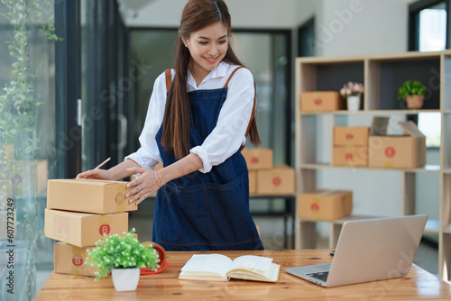 Starting small business entrepreneur of independent young Asian woman online seller is using computer and taking orders to pack products for delivery to customers. SME delivery concept