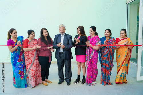 Senior businessman cutting red ribbon with women employee group. inauguration concept. photo