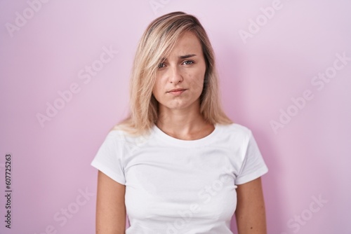 Young blonde woman standing over pink background skeptic and nervous, frowning upset because of problem. negative person.
