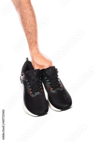 Pair of new unbranded black sport running shoes or sneakers in male hand isolated on white background with clipping path
