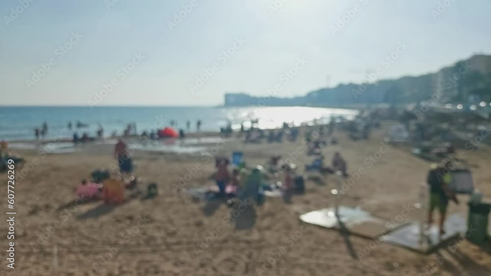View of a sunny beach in out of focus. People are sunbathing and swimming in the sea. View of a sunny beach in out of focus. People are sunbathing and swimming in the sea.