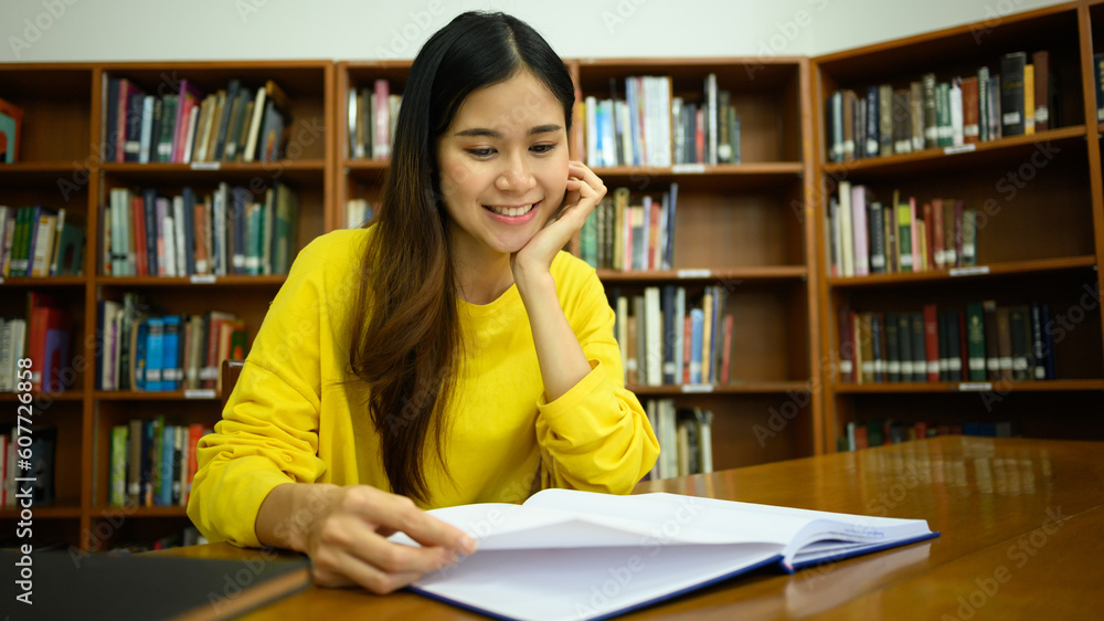 Pleased female student reading book in a library for studying and research. Education, learning, knowledge and university Pleased female student reading book in a library for studying and research. Education, learning, knowledge and university
