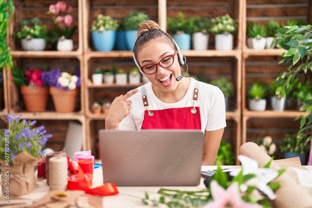 Young hispanic woman working at florist shop doing video call smiling happy pointing with hand and finger Young hispanic woman working at florist shop doing video call smiling happy pointing with hand and finger