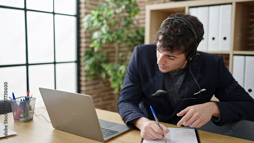 Young hispanic man business worker wearing headset taking notes at office Young hispanic man business worker wearing headset taking notes at office