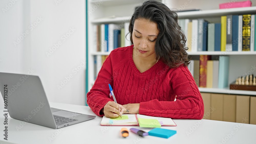 Young beautiful hispanic woman student using laptop writing notes at library university Young beautiful hispanic woman student using laptop writing notes at library university