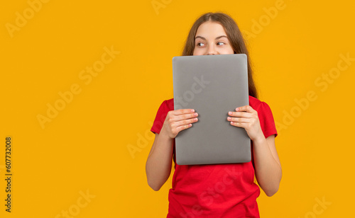 cheerful girl behind laptop on yellow background