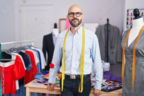 Young bald man tailor smiling confident standing at tailor shop