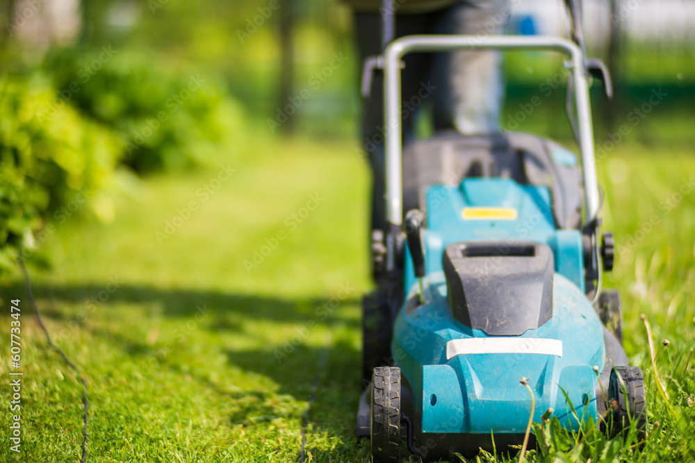 Lawn mover on green grass in modern garden or backyard. Machine for cutting lawns. Gardening care tools and equipment Lawn mover on green grass in modern garden or backyard. Machine for cutting lawns. Gardening care tools and equipment