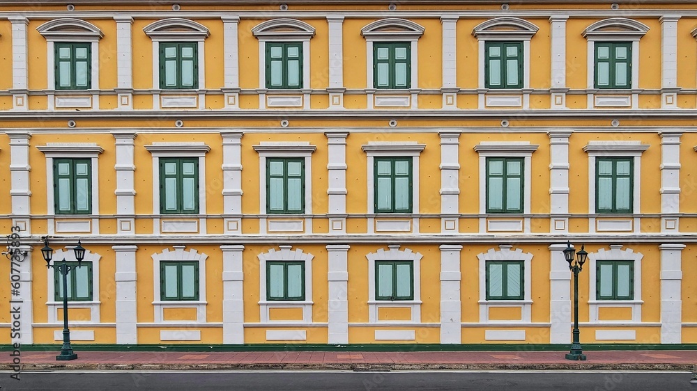 Multiple closed windows on yellow large building wall