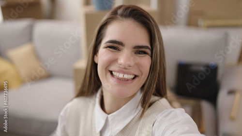 Young beautiful hispanic woman smiling taking selfie at new home