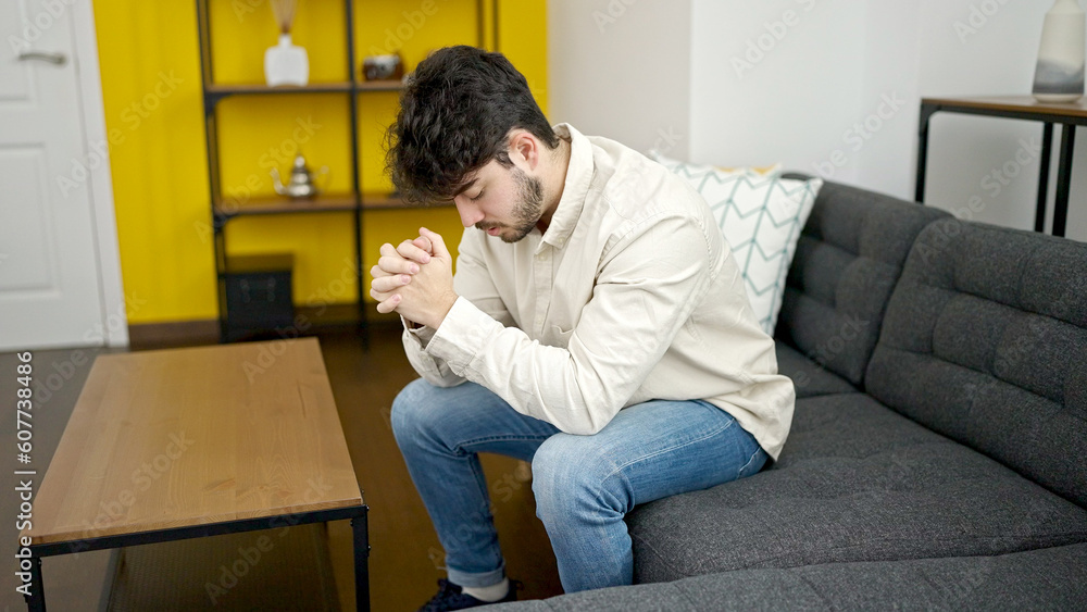 Young hispanic man stressed sitting on sofa at home Young hispanic man stressed sitting on sofa at home