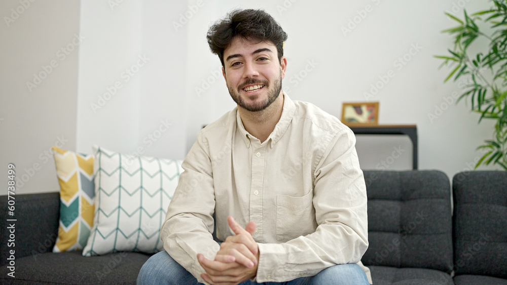 Young hispanic man smiling confident sitting on sofa at home