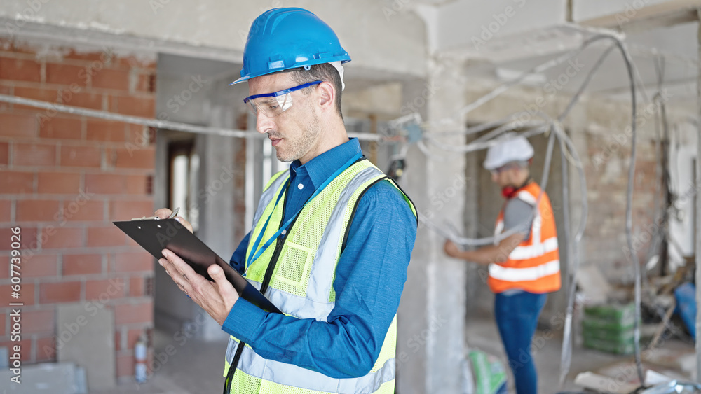 Two men builders writing document working at construction site Two men builders writing document working at construction site