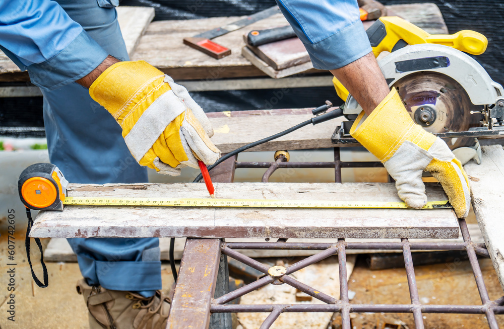 Fototapeta premium Construction worker are using tape measurements to measure planks and pencil are used to write, Close up of male hands measuring wood flooring, Construction industry, housework do it yourself..