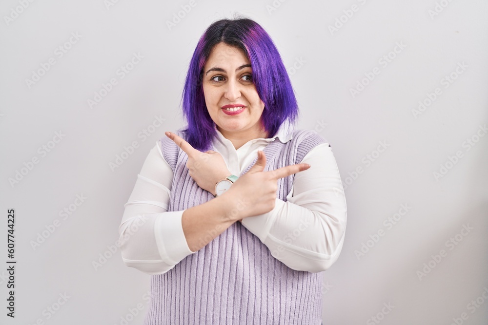 Plus size woman wit purple hair standing over white background pointing to both sides with fingers, different direction disagree Plus size woman wit purple hair standing over white background pointing to both sides with fingers, different direction disagree