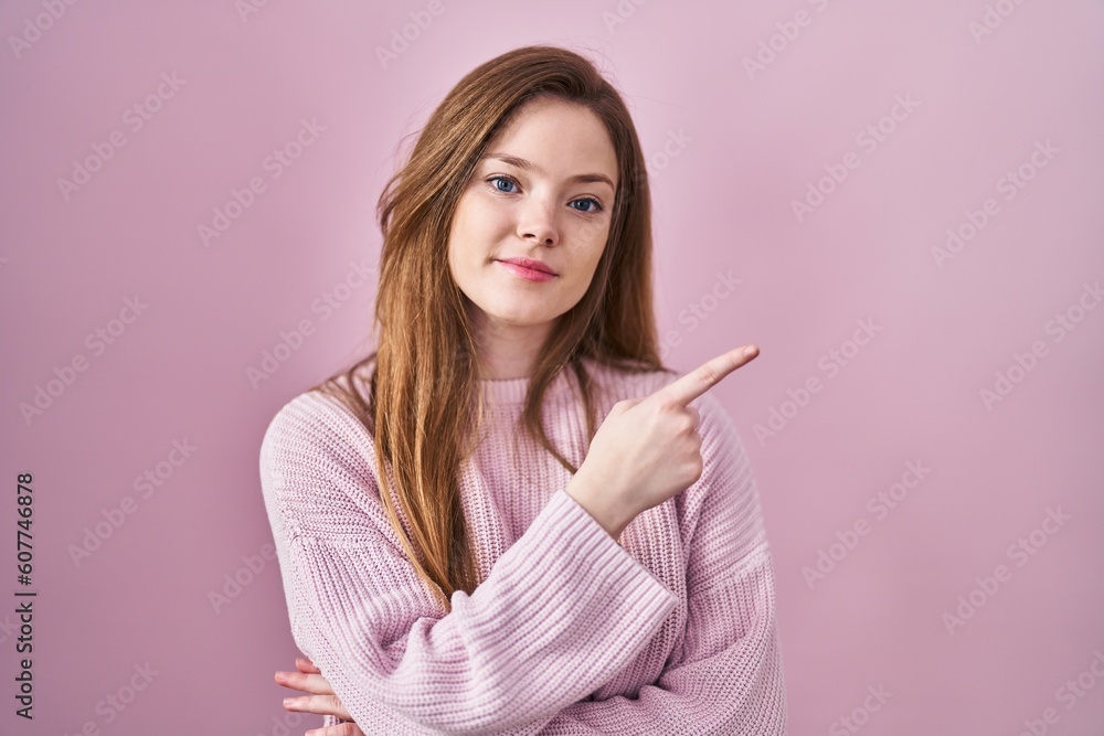 Young caucasian woman standing over pink background pointing with hand finger to the side showing advertisement, serious and calm face Young caucasian woman standing over pink background pointing with hand finger to the side showing advertisement, serious and calm face