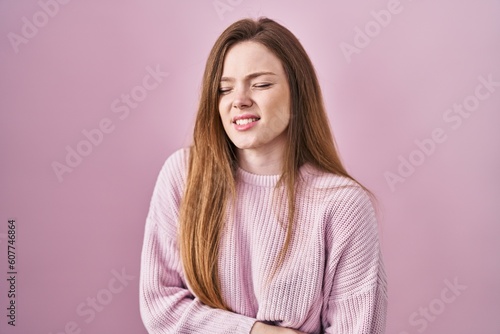 Young caucasian woman standing over pink background with hand on stomach because indigestion, painful illness feeling unwell. ache concept.