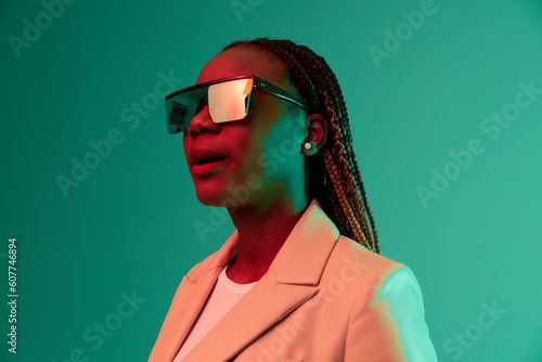 African american woman smile and fashion wearing glasses green background in neon light color mixed light, bright color dancing, futuristic party. Beauty African American woman with pigtails emotions. © SHOTPRIME STUDIO