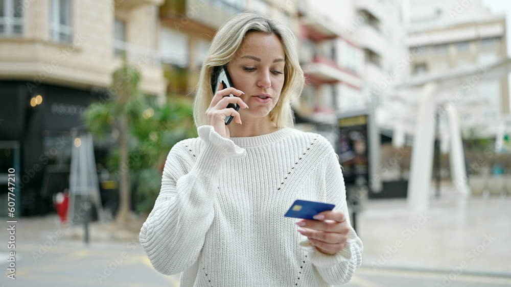 Young blonde woman talking on smartphone holding credit card at street Young blonde woman talking on smartphone holding credit card at street