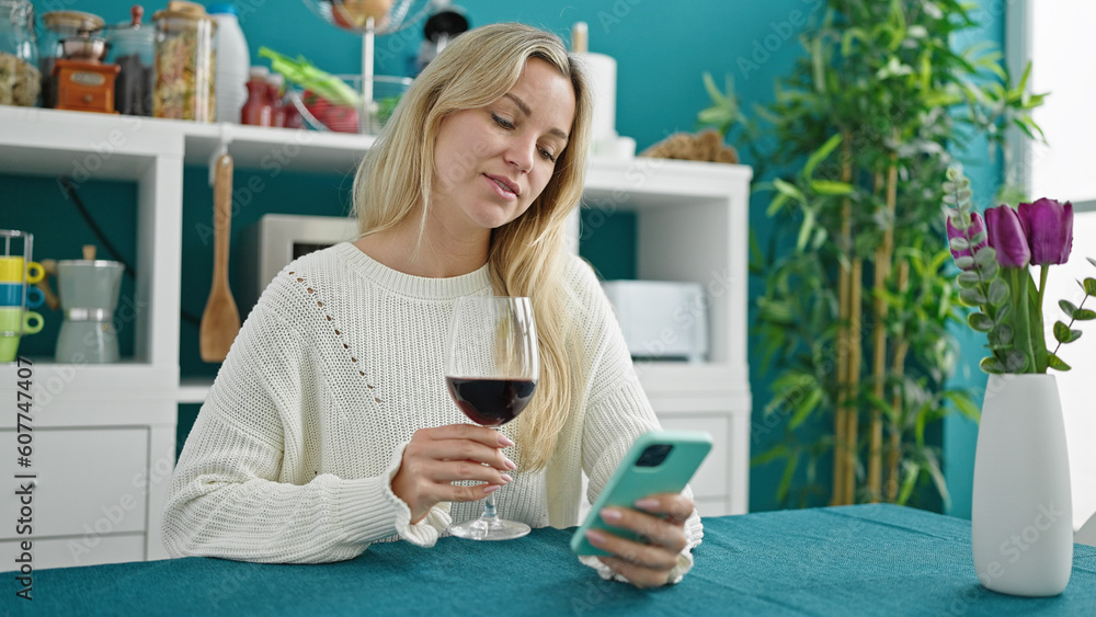 Young blonde woman drinking glass of wine using smartphone at dinning room Young blonde woman drinking glass of wine using smartphone at dinning room