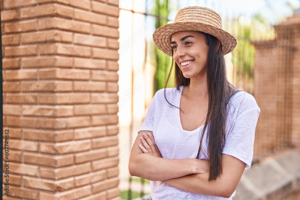 Young hispanic woman tourist smiling confident standing with arms crossed gesture at street