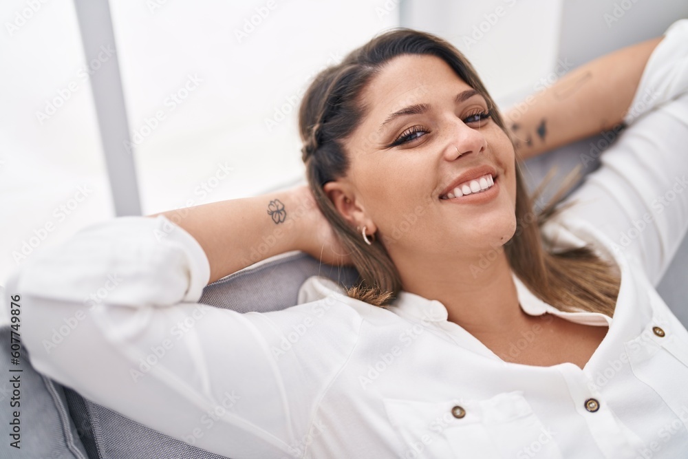 Young hispanic woman relaxed with hands on head sitting on sofa at home Young hispanic woman relaxed with hands on head sitting on sofa at home
