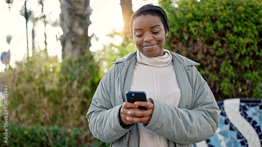 African american woman using smartphone smiling at park African american woman using smartphone smiling at park