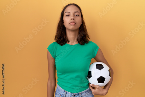 Young hispanic woman holding ball relaxed with serious expression on face. simple and natural looking at the camera. © Krakenimages.com