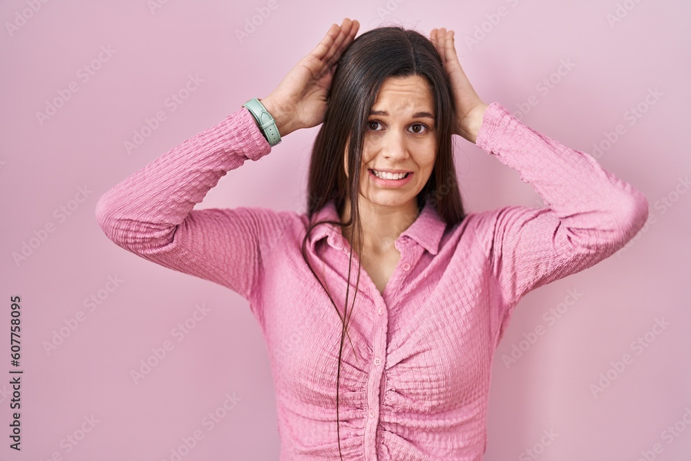 Young hispanic woman standing over pink background doing bunny ears gesture with hands palms looking cynical and skeptical. easter rabbit concept.
