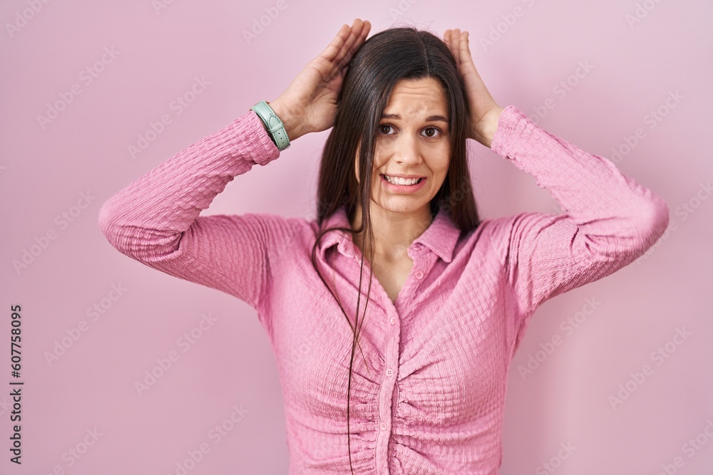 Young hispanic woman standing over pink background doing bunny ears gesture with hands palms looking cynical and skeptical. easter rabbit concept. Young hispanic woman standing over pink background doing bunny ears gesture with hands palms looking cynical and skeptical. easter rabbit concept.
